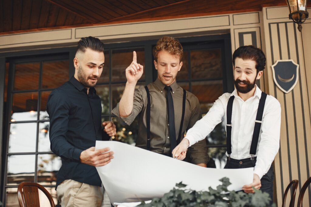 mens discussing plans while looking at a blueprint outdoors